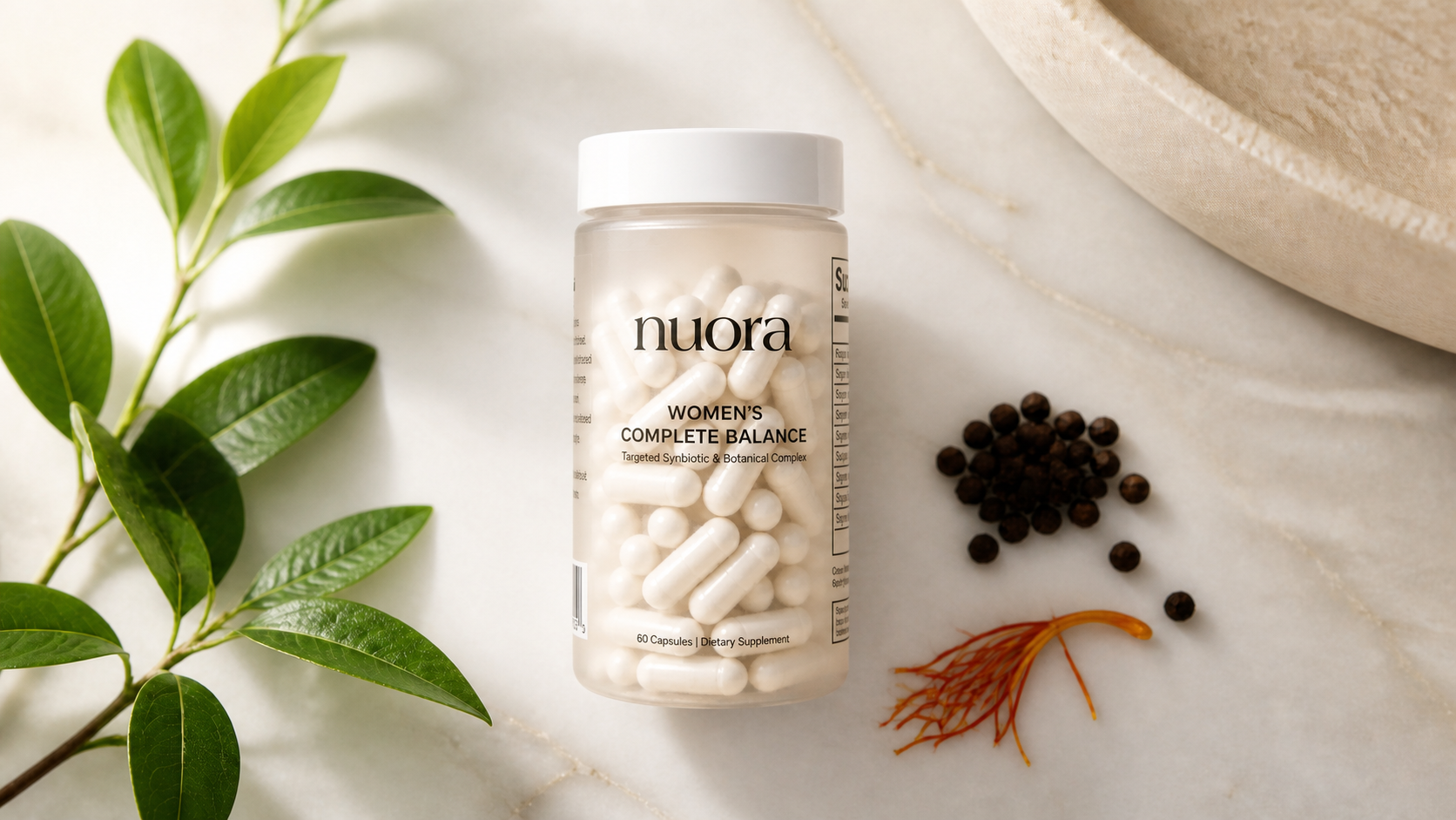 Nuora Women's Complete Balance capsules on a warm marble surface with botanical leaves, peppercorns and saffron